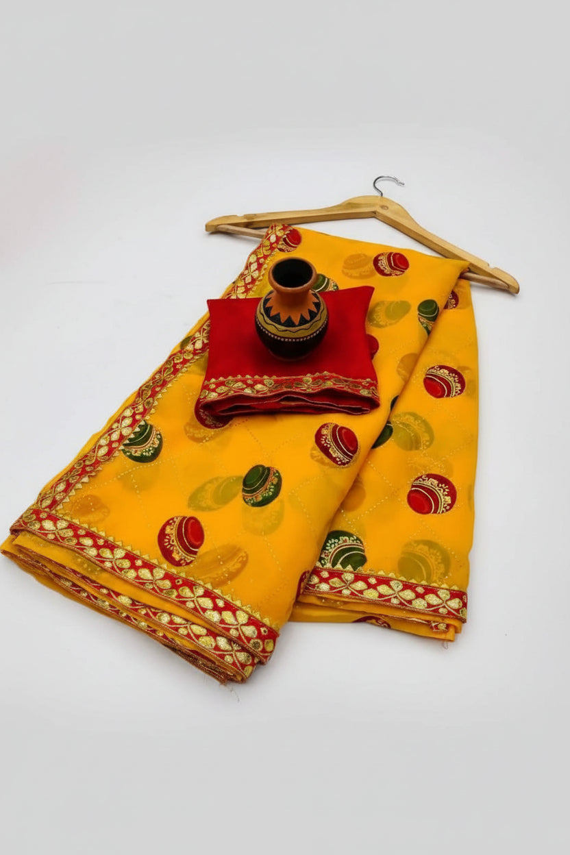 A folded yellow traditional fabric set with red and gold borders, decorated with green and red motifs, displayed on a white background with a wooden hanger and a small decorative pot.